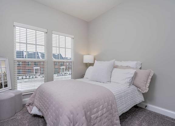 A bedroom with a large bed and a window overlooking a cityscape.