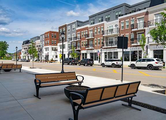 A row of benches are lined up on a sidewalk.