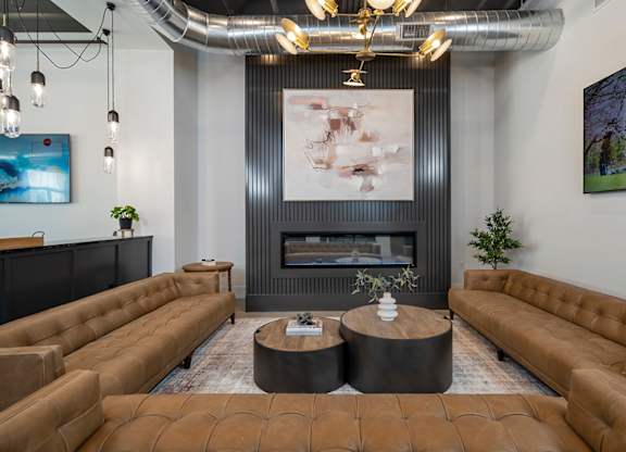 A modern living room with a fireplace and brown leather couches.
