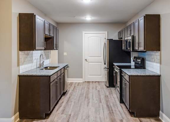 A kitchen with dark brown cabinets and a black refrigerator at Mode at Melbourne, LLC Apartments, Florida, 32901