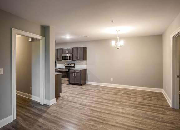 A kitchen with a refrigerator, microwave, and oven is visible through a glass door at Mode at Melbourne, LLC Apartments, Melbourne, FL, 32901