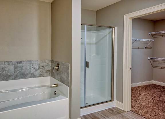 A bathroom with a white bathtub and a glass shower door at Mode at Melbourne, LLC Apartments, Melbourne, 32901