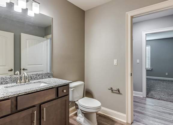 A bathroom with a toilet, sink, and mirror at Mode at Melbourne, LLC Apartments, Florida