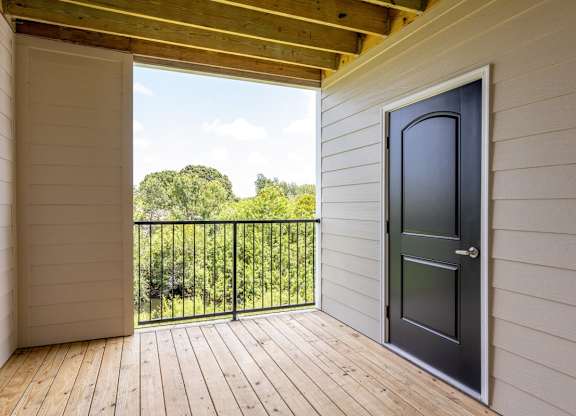 A balcony with a black door and a view of trees at Mode at Melbourne, LLC Apartments, Florida, 32901
