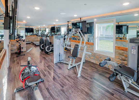 A gym with a variety of equipment including a stationary bike, a leg press machine, and a cable machine at Mode at Melbourne, LLC Apartments, Melbourne, 32901