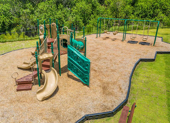 A playground with a green fence and a yellow slide at Mode at Melbourne, LLC Apartments, Florida, 32901