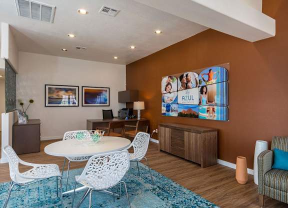 A living room with a white table and chairs, a blue rug, and a brown cabinet.