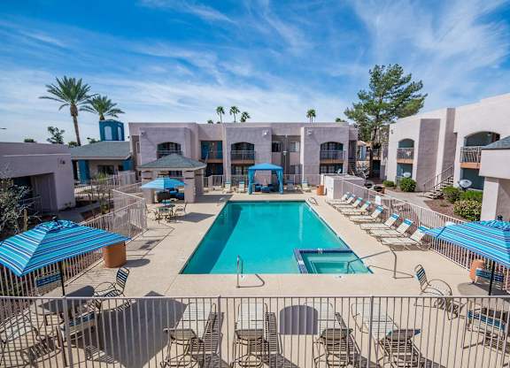 A large swimming pool surrounded by lounge chairs and umbrellas.