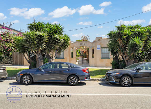 Two cars parked in front of a building with the logo of Beach Front Property Management.