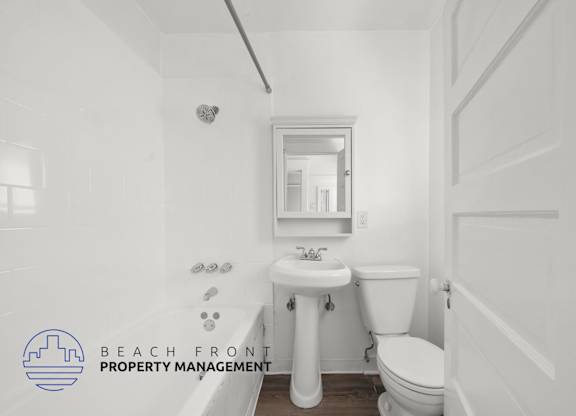 A white bathroom with a toilet, sink, and mirror.