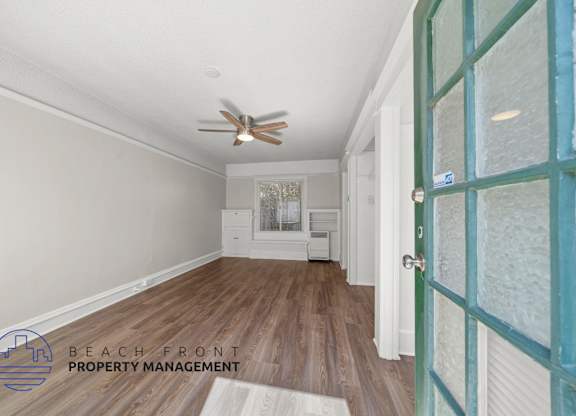 A room with a ceiling fan and wooden flooring.