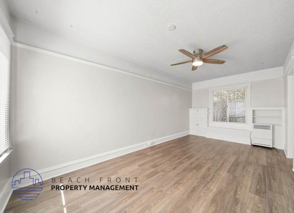 A room with a ceiling fan and wooden flooring.
