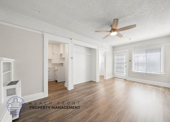 A spacious room with a ceiling fan and wooden flooring.