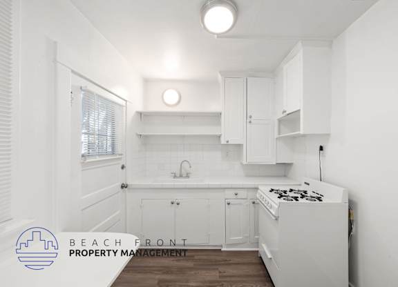 A kitchen with white cabinets and a stove top oven.