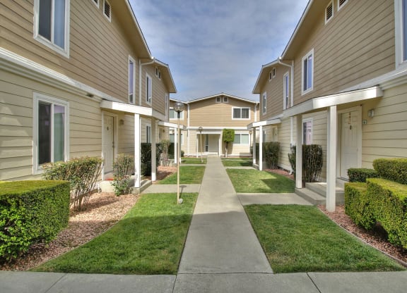 A long, narrow walkway separates apartment buildings.