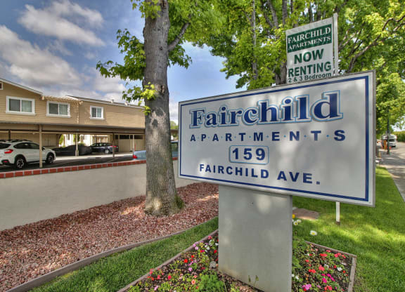 A sign for Fairchild Apartments stands in front of a building.