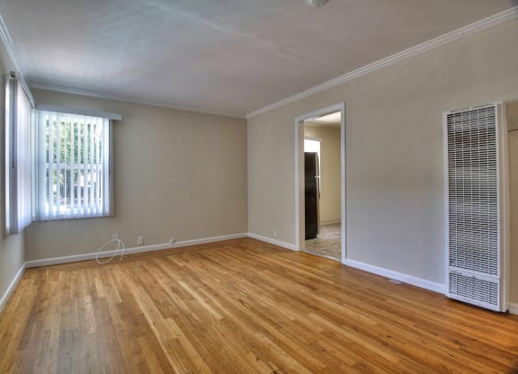 A room with wooden floors and a window with blinds.