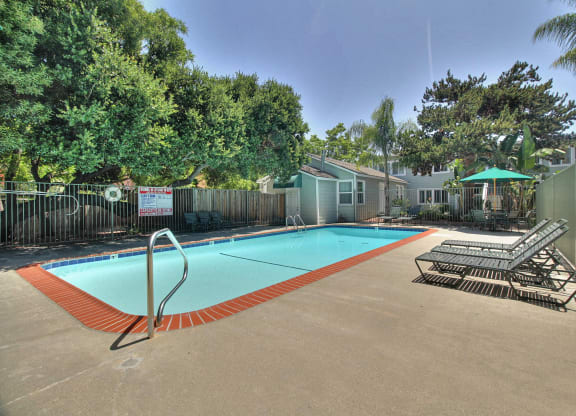 A pool surrounded by trees and a fence with a sign on it.