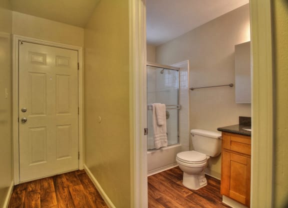 A white door is in a room with a toilet and a shower.