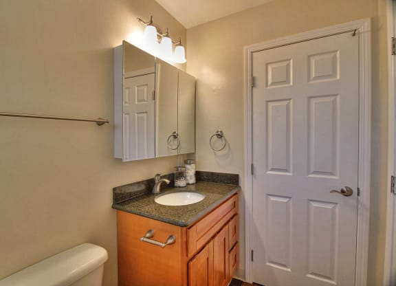 A bathroom with a toilet, sink, and mirror.
