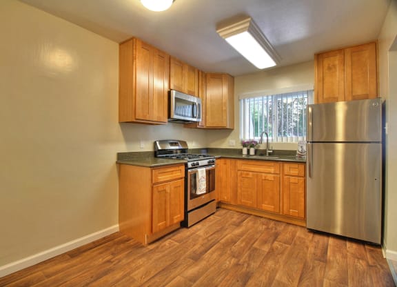 A kitchen with wooden cabinets and a stainless steel refrigerator.