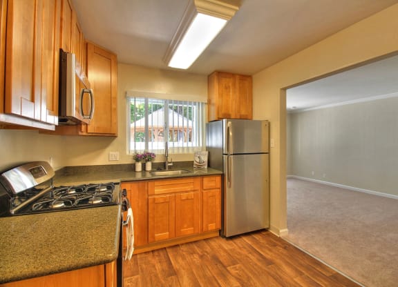 A kitchen with wooden cabinets and a stainless steel refrigerator.
