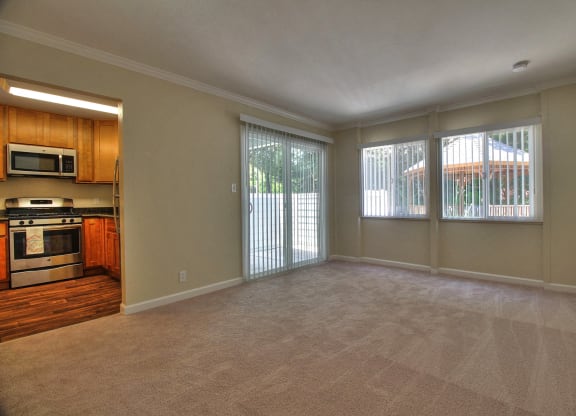 A spacious living room with a kitchen area to the left and sliding glass doors to the right.