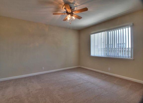 A room with a ceiling fan and a window with blinds.