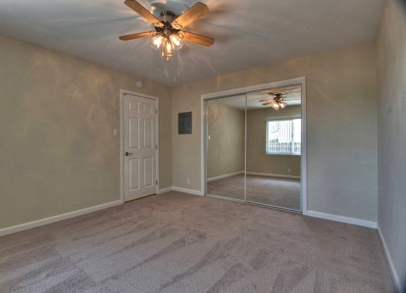 A room with a ceiling fan and carpeted floor.