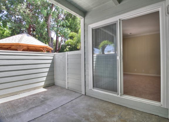 A patio with a sliding glass door leading to a room.