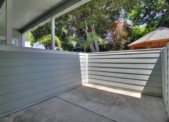 A patio with a grey wall and a white slatted fence.