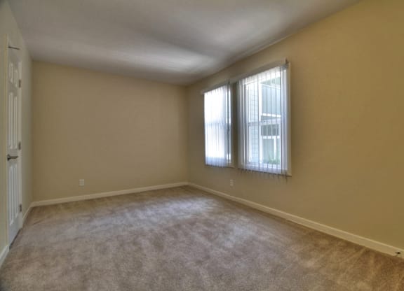 A room with a carpeted floor and a window with blinds.