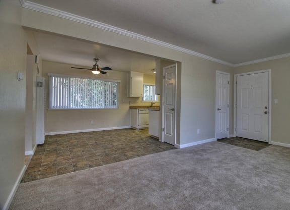 an empty living room and kitchen with a ceiling fan