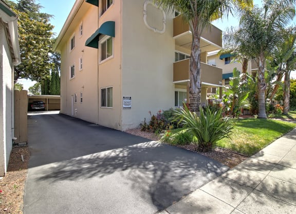 a beige apartment building with a driveway and palm trees