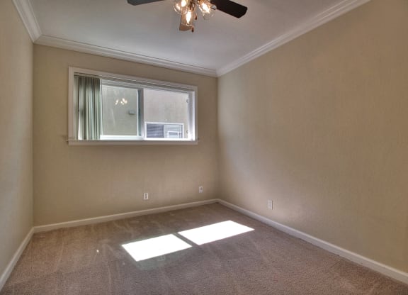 A room with a window and a ceiling fan.