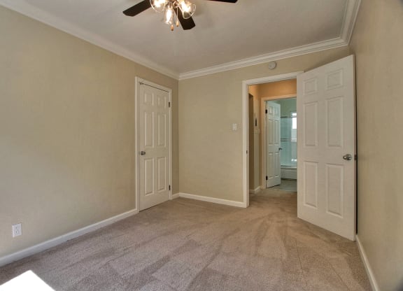 A room with a ceiling fan and carpeted floor.