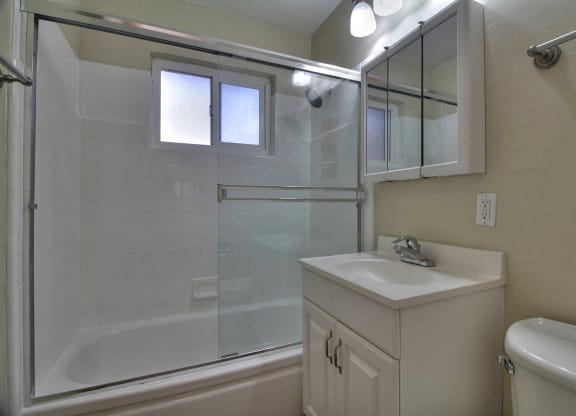 A white sink is on a white cabinet in a white bathroom.