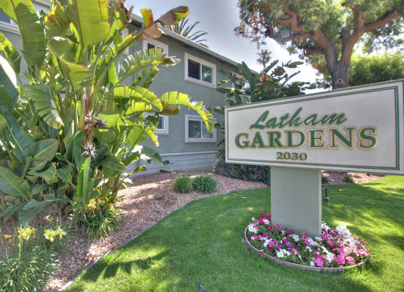 A sign for Latham Gardens stands in a well-kept garden.