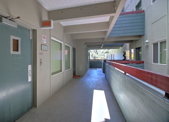 A long hallway with a red line on the wall and an elevator in the distance.