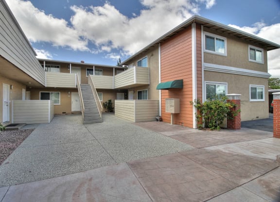 Apartment complex with a concrete walkway in front.