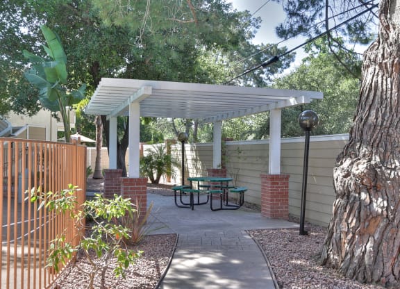 A patio with a table and chairs under a white pergola.