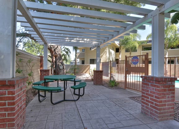 A patio with a green table and chairs under a white pergola.