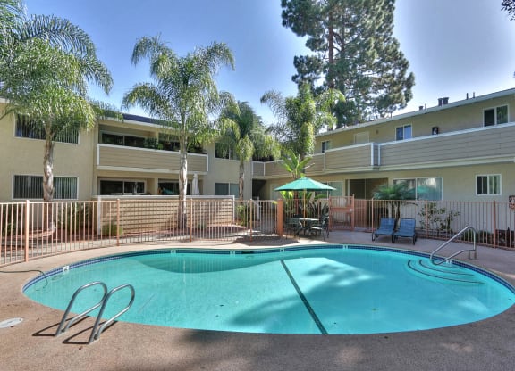A swimming pool surrounded by palm trees and apartment buildings.