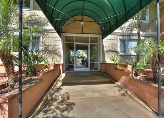 A covered walkway with a green canopy and a stone floor.
