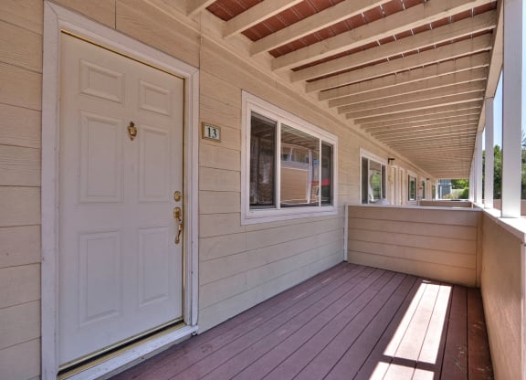 a covered porch of a home with a white door