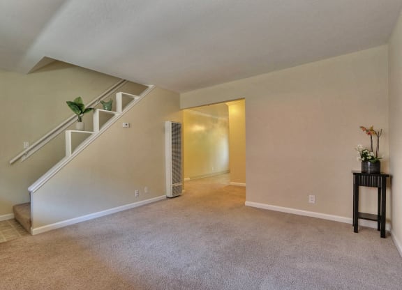 a living room with a staircase and a carpeted floor