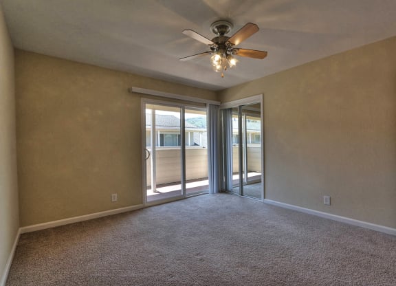 an empty living room with a ceiling fan and sliding glass doors