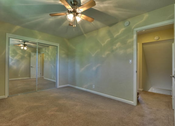 a bedroom with a ceiling fan and a mirrored closet