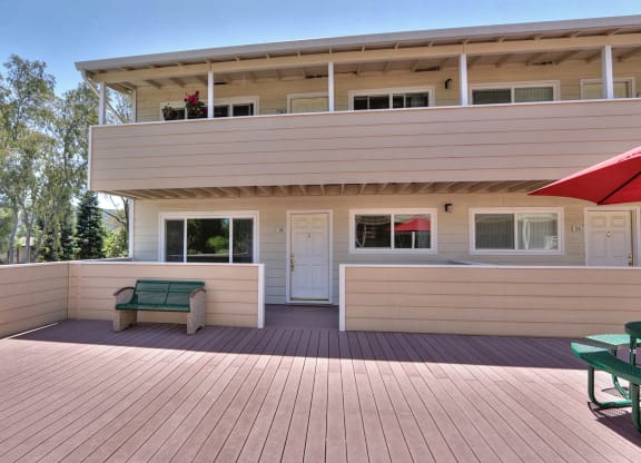 a large deck in front of a house with a bench on it