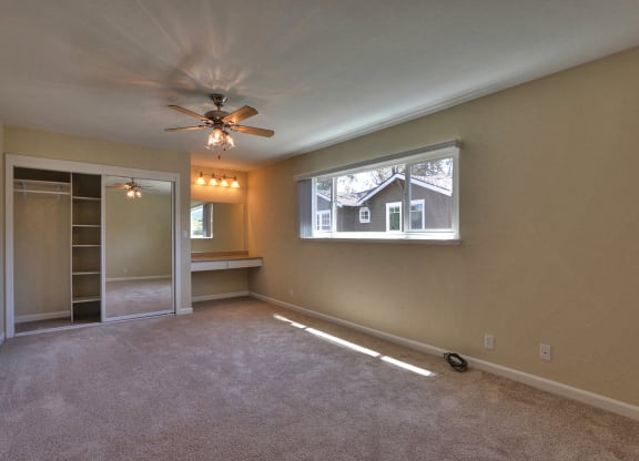 an empty living room with a ceiling fan and a window